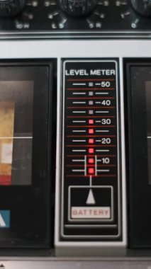 Kırmızı göstergeli retro boomboxların dikey yakın çekimi, analog ses teknolojisini gösteriyor.