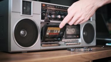 Bir el, analog müziğin klasik seslerinden zevk almaya hazır klasik bir müzik kutusuna bir kaset yerleştirir..