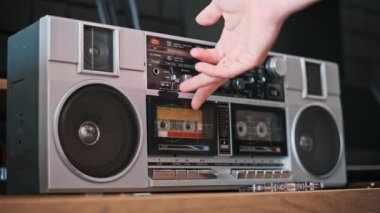 İçinde kaset olan klasik gümüş bir teyp, geçmişten gelen melodileri çalmaya hazır ahşap bir yüzeye oturur..