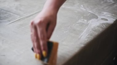 Yemek pişirdikten sonra, temizlik ve hijyeni vurgulayarak gri mutfak masasından un temizlemek için sünger kullanan sarı tırnaklı bir kadının yakın çekim görüntüleri..