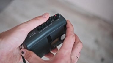 Bir adam taşınabilir bir kasetçalara antika bir ses kaseti yerleştiriyor, nostalji ve analog müzik çağrıştırıyor..