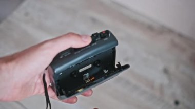Elinde antika bir kasetçalar tutan bir adamın yakın plan görüntüleri. Tasarımı, düğmeleri ve yerleştirilmiş kaset kaseti sergileniyor..