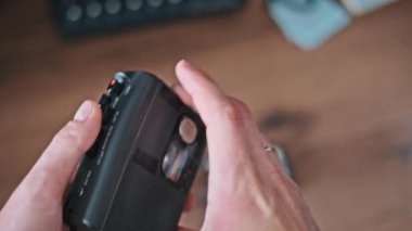 Kapatma mekanizmasının tatmin edici tıklamasını vurgulayan bir kaset çaları yerleştirdikten sonra bir adamın portatif bir kasedi kapattığı yakın çekim görüntüleri.