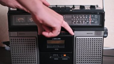 Bir adam, antika bir müzik kutusundan bir ses kaseti yerleştirir ve kaldırır. Bu antika teknolojinin bu ikonik parçası ile dokunsal etkileşimi gösterir..
