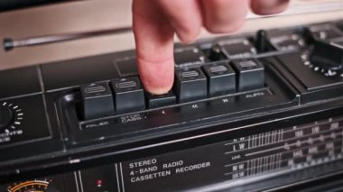 Bir el klasik bir teybin akort düğmesini ayarlar, radyo dalgaları arasında bir radyo istasyonunu dikkatle arar. Bu nostaljik sahne analog radyo ayarlarının özünü yakalıyor..
