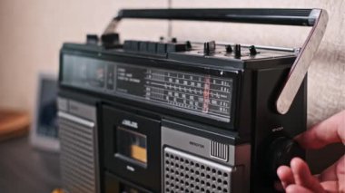 Bir el klasik bir radyonun akort düğmesini ayarlar, net bir sinyal ve mükemmel bir istasyon arar. Görüntü, müziğin radyo dalgaları aracılığıyla keşfedildiği bir zaman için nostalji hissi uyandırıyor.