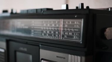Klasik bir radyo kanalının dikkatlice ayarlanmış yakın plan görüntüsü. Kırmızı çizgi frekanslar arasında hareket ediyor. Eski moda teknolojinin cazibesi ve mükemmel bir istasyon arayışına işaret ediyor..