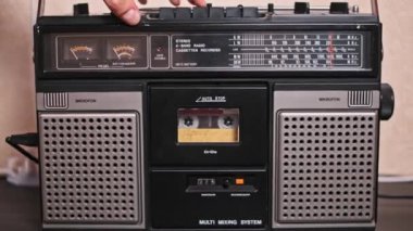 Bir el dikkatle klasik bir kaseti müzik çalmaya hazır bir teybe yerleştirir. Yakın çekim analog teknolojinin dokunsal deneyimini ve nostaljik çekiciliğini vurguluyor..
