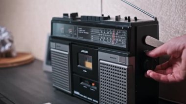 Bir el klasik bir radyonun akort düğmesini ayarlar, net bir sinyal ve mükemmel bir istasyon arar. Görüntü, müziğin radyo dalgaları aracılığıyla keşfedildiği bir zaman için nostalji hissi uyandırıyor.
