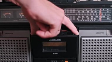 Bir el, kaseti dikkatlice klasik bir teybe yerleştirir, çalmaya hazırdır. Görüntü analog ses teknolojisinin dokunsal deneyimini vurgular.