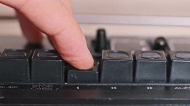 Bir parmak çalma tuşunu çalıştırır, ardından da klasik bir teybin stop düğmesi. Yakın çekim görüntüsü bu klasik kontrollerin tatmin edici tıklamasını vurguluyor, nostalji hissi uyandırıyor..