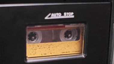 Müzik kutusunda dönen klasik bir kasetin yakın çekimi, makaralar dönüyor, analog müziğin büyüleyici bir görüntüsünü oluşturuyor..