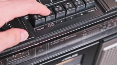 Bir el klasik bir kaseti analog müziğin klasik sesinin tadını çıkarmaya hazır bir teybe yüklüyor. Karışık kasetlerin ve taşınabilir müzik çalarlarının hatıralarını sevenler için nostaljik bir imaj..