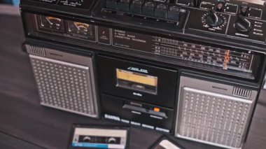 Bir el dikkatle klasik bir kaseti müzik çalmaya hazır bir teybe yerleştirir. Yakın çekim analog teknolojinin dokunsal deneyimini ve nostaljik çekiciliğini vurguluyor..
