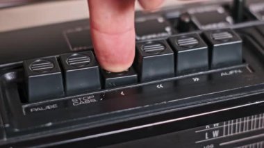 Bir parmak çalma tuşunu çalıştırır, ardından da klasik bir teybin stop düğmesi. Yakın çekim görüntüsü bu klasik kontrollerin tatmin edici tıklamasını vurguluyor, nostalji hissi uyandırıyor..