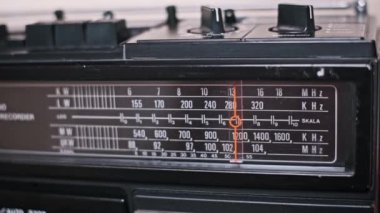 Bir el, eski bir radyonun akort düğmesini ayarlar, analog kadranda bir istasyonu dikkatle arar. Radyo yayınları ve yeni müzikler keşfetme heyecanı nostaljiyi çağrıştırıyor..