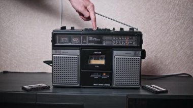 Bir el klasik bir boombox ile etkileşime girer, çalma düğmesine basar ve durdurma düğmesine basar, analog ses kontrolünün basitliğini gösterir. Görüntü, geçmiş bir çağ için nostalji hissi uyandırıyor..