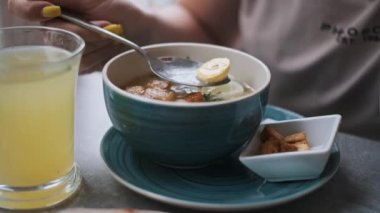 Sarı tırnaklı, kızarmış tavuk çorbası, yanında yumurta ve limonata içen bir kadının yakın çekimi. Kafe yemek sahnesi.