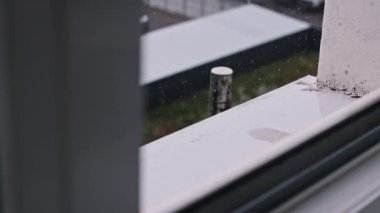 Şiddetli yağmurun pencere eşiğine düşüşünün yavaş çekim görüntüleri şehir caddesini bulanıklaştırıyor. Dramatik ve atmosferik bir sahne oluşturur.