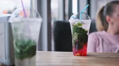 Kafedeki ahşap bir masada plastik bir bardakta çilekli mojito kokteyli tazeliyorum. Naneli, limonlu ve buzlu yaz içeceği.