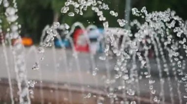 Bu yavaş çekim görüntüsü, fıskiyeden zarifçe yayılan su jetlerinin zarafetini yakalar, güzel bir bokeh efektiyle bulanık arka planda parlayan damlacıkları vurgular..