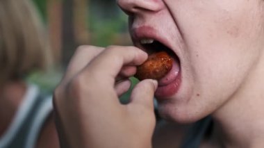 Sağlıksız yeme alışkanlıklarını ve fast food 'un cazibesini vurgulayan şımarık bir tavuk nuggetını ısıran bir gencin yakın plan çekimi..