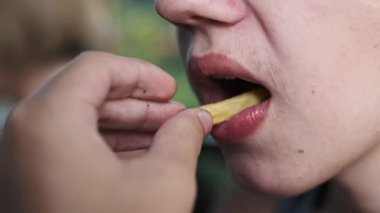 Elleriyle patates kızartması yiyen bir çocuğun yakın plan fotoğrafı. Sıradan yemek ve sağlıksız yemek kavramı..