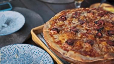 Sosisli ve erimiş peynirli lezzetli bir pizza, ahşap tezgahta servis edilir, eğlenmeye hazır..