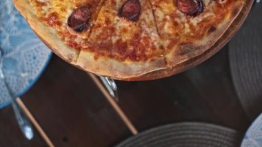 Sosisli ve erimiş peynirli lezzetli bir pizzanın en üst görüntüsü, ahşap tezgahta servis ediliyor, yemek fotoğrafçılığı ve aşçılık projeleri için mükemmel..