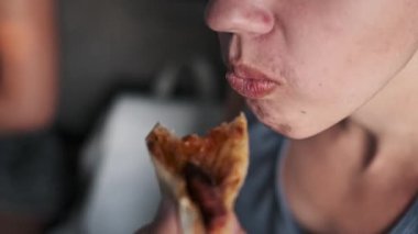 Küçük bir çocuğun bir dilim pizzanın tadını çıkarırken, fast food 'un neşesini ve şımarıklığını ön plana çıkarırken yakın çekim..