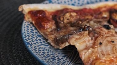Tabakta mantar, soğan ve sosis olan bir dilim pizzayı yakın. Akşam yemeğinden sonra kalan yemekler..