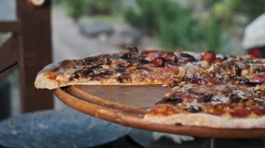 Ağız sulandıran, kıtır kıtır sosisli, mantarlı ve soğanlı bir pizza, ahşap bir stantta sunuluyor..