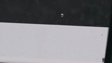 Çatı kenarından düşen yağmur damlalarının sakin, yavaş çekim görüntüleri bulanık bir kırsal zemine karşı hareket halindeki su damlacıklarının güzelliğini gösteriyor..