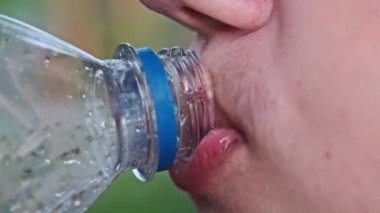 Plastik şişeden soda içen bir çocuğun yakın plan fotoğrafı, çocuklar için sağlıksız içecek, şeker bağımlılığı konsepti..