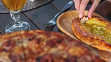 Geleneksel bir Gürcü yemeği olan Adjarian Khachapuri, eritilmiş peynir, yumurta sarısı ve koparılmış bir parça ile ahşap bir tabakta servis edildi. Lezzetli ve peynirli yemek..