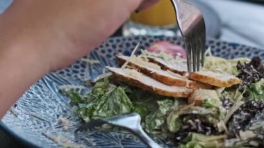 Bir restoranda Sezar salatası yemek için çatal kullanan kadınların yakın plan fotoğrafları. Sağlıklı ve lezzetli yemek konsepti..