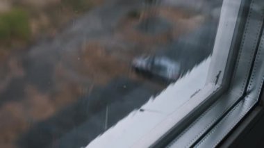 Pencere camından dökülen yağmur damlalarının yakın plan görüntüsü bulanık bir arkaplanda büyüleyici bir su damlası görüntüsü oluşturur..