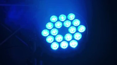 Dinamik bir LED sahne ışığı dumanlı bir çevreyi aydınlatır, canlı mavi ve turkuaz renkler arasında sorunsuzca geçiş yapar.