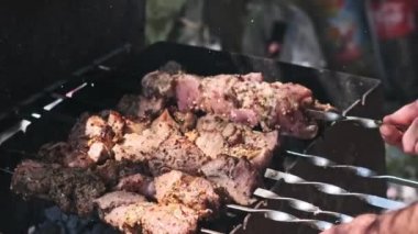Salamura edilmiş et parçaları sıcak kömürlerin üzerinde cızırdıyor, bir adam onları ustalıkla çeviriyor, lezzetli ve eşit derecede pişirilmiş bir barbekü ikram ediyor..