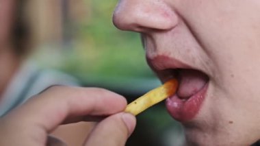 Kıtır kıtır patates kızartması yiyen bir çocuğun yavaş çekim görüntüsü, bu popüler atıştırmalığın dokusunu ve basit zevkini yakalıyor..