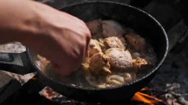 Şef dışarıda kamp ateşinde soğanlı et pişiriyor..