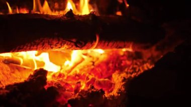 Şöminede yanan bir kütüğün yakın çekimi, yoğun turuncu alevler büyüleyici bir manzara yaratıyor. Kış, sıcaklık, ev ve rahat ortam projeleri için mükemmel..