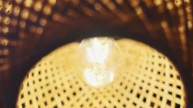 Bir bambu fenerinin yakın plan görüntüsü yapının karmaşık dokumasını ve içindeki ampulün sıcak parıltısını ortaya çıkarır..