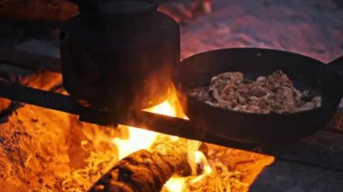 Kükreyen bir kamp ateşinin üzerinde bir tavukla bir çaydanlık kaynıyor, samimi ve davetkar bir ortam yaratıyor. Kamp, açık hava yemekleri ve macera projeleri için idealdir..