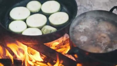Bir tencere patates, bir tencere kabağın yanında kaynatılır. Kamp ateşinin üzerinde dilimler. Açık havada hazırlanmış basit ama lezzetli bir yemek sergilenir..