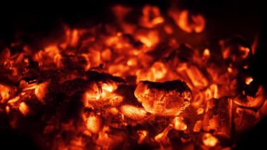 Karanlıkta yoğun bir şekilde parlayan kızgın közlerin yakın çekimi alevler sönse bile hala mevcut olan ısı ve enerjiyi gözler önüne seriyor..