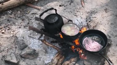 Tencerede çorba pişirme ve kamp ateşinde tavada yağ kızartma manzarası..