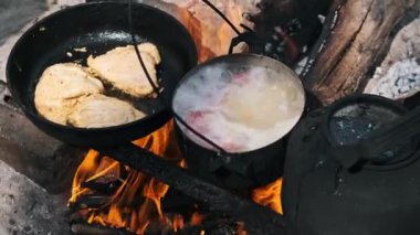 Tavada tavuk kızartma ve kamp ateşinin üstünde çorba kaynıyor. Lezzetli ve kolay açık hava yemekleri..