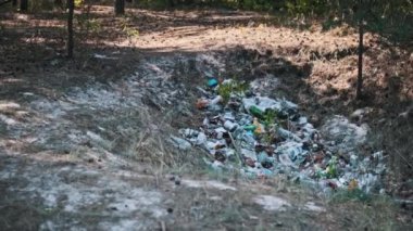 Plastik, cam şişeler, kağıt ve diğer atıklar da dahil olmak üzere büyük bir çöp yığını, yasadışı boşaltmanın yol açtığı çevresel hasarı gösteren bir hendek oluşturuyor..
