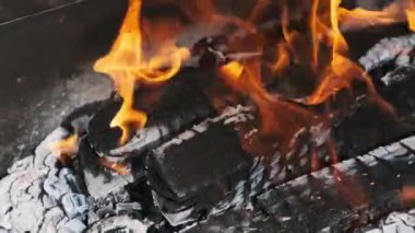 Alevli bir kamp ateşinin yakın plan çekimi, canlı alevler, parlayan közler ve büyüleyici ateş dansı. Sıcaklığı, enerjiyi ve açık hava ortamını taşımak için mükemmel..